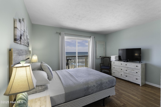 bedroom featuring dark hardwood / wood-style flooring, access to outside, and a textured ceiling