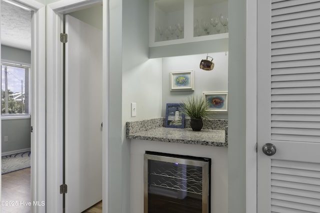 bar featuring wine cooler and light stone counters