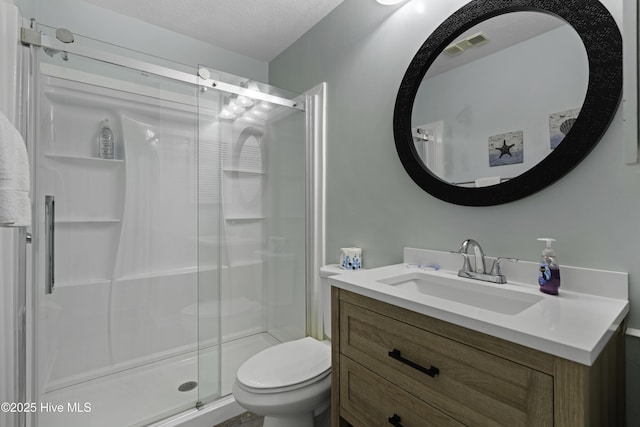 bathroom with toilet, vanity, a textured ceiling, and a shower with shower door