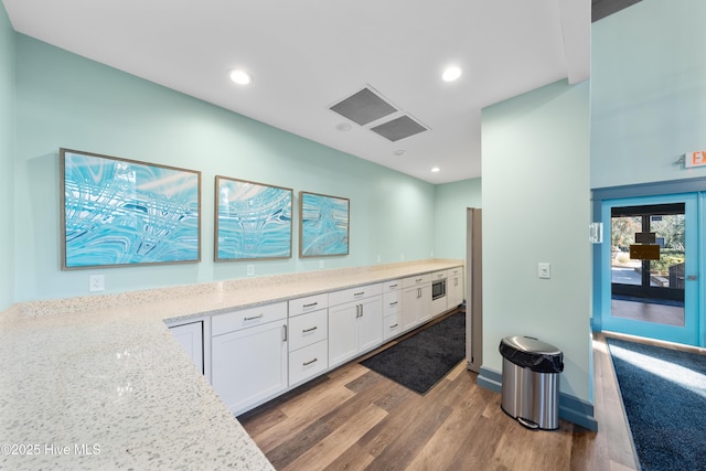 kitchen with white cabinetry, light stone counters, light hardwood / wood-style floors, and stainless steel refrigerator