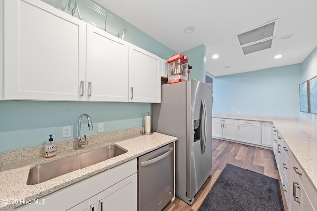 kitchen featuring sink, white cabinetry, stainless steel appliances, light stone countertops, and dark hardwood / wood-style flooring