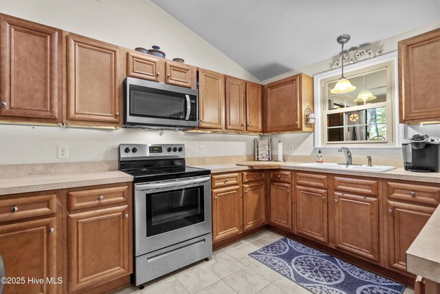 kitchen with lofted ceiling, appliances with stainless steel finishes, brown cabinets, light countertops, and a sink