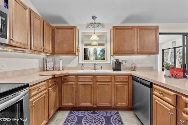 kitchen with pendant lighting, light countertops, appliances with stainless steel finishes, brown cabinetry, and a sink