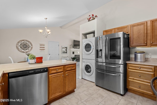 kitchen featuring appliances with stainless steel finishes, stacked washer and dryer, light countertops, and hanging light fixtures