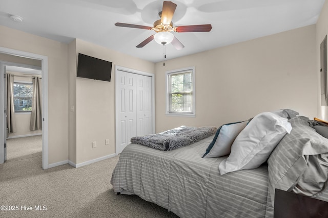 bedroom featuring light carpet, a closet, a ceiling fan, and baseboards