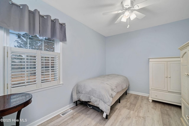 bedroom with ceiling fan, multiple windows, and light hardwood / wood-style flooring