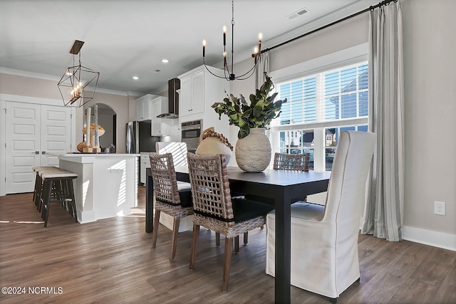 dining space with ornamental molding, an inviting chandelier, and dark hardwood / wood-style flooring