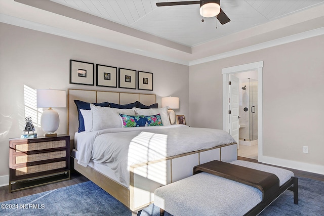 bedroom featuring crown molding, ensuite bathroom, dark hardwood / wood-style flooring, and a tray ceiling