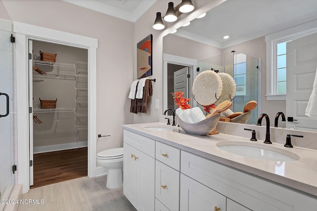 bathroom with vanity, ornamental molding, a shower with door, and toilet