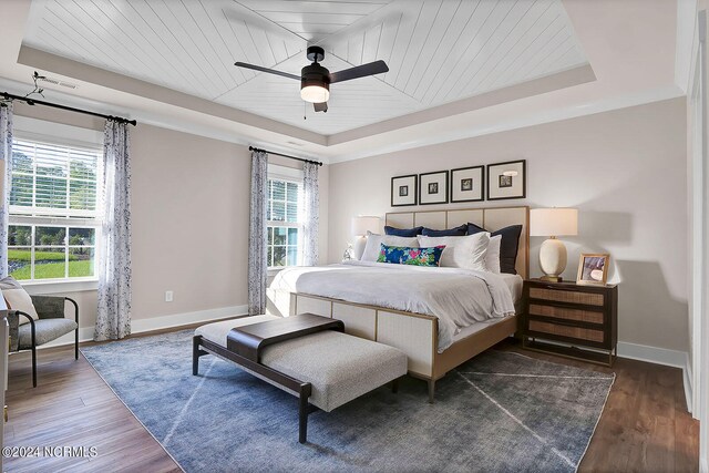 bedroom with dark hardwood / wood-style floors, a tray ceiling, multiple windows, and wooden ceiling