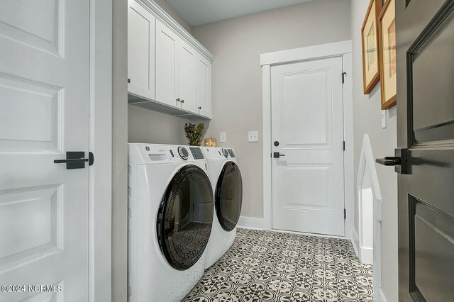 laundry area featuring cabinets, light tile patterned floors, and washer and clothes dryer