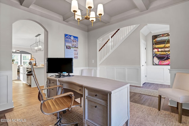 office space featuring an inviting chandelier, coffered ceiling, beam ceiling, and light hardwood / wood-style flooring