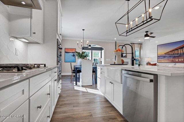 kitchen featuring stainless steel appliances, white cabinetry, hardwood / wood-style flooring, and pendant lighting