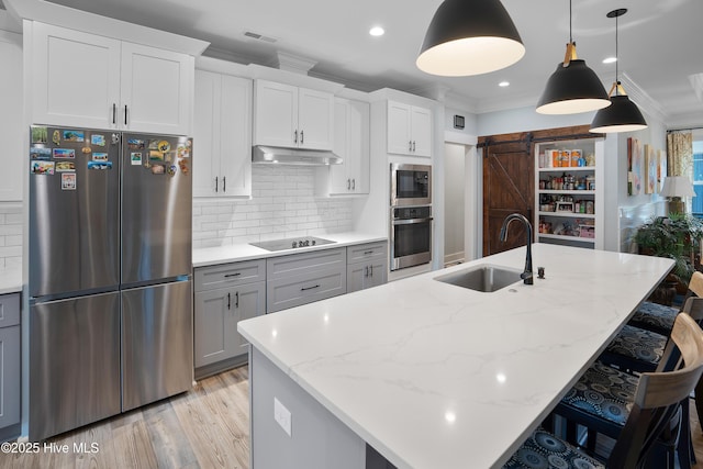 1611 Golfers Ridge Dr SE, Bolivia, NC 28422 - kitchen with stainless steel appliances, a barn door, ornamental molding, under cabinet range hood, and a breakfast bar area