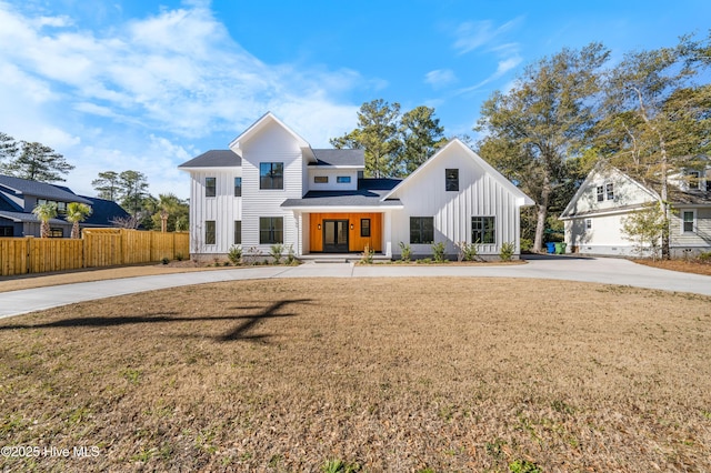 modern farmhouse with fence, board and batten siding, and a front yard