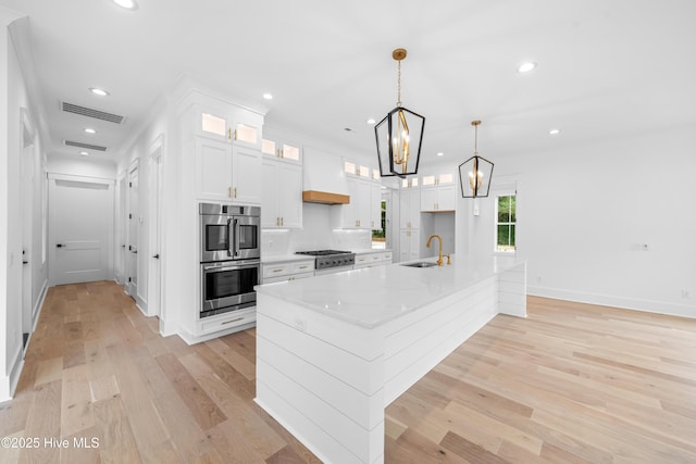 kitchen with sink, white cabinets, custom exhaust hood, stainless steel appliances, and a spacious island