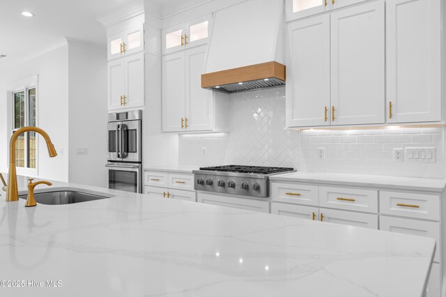 kitchen with premium range hood, sink, and white cabinets