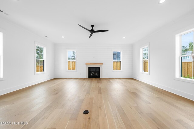 unfurnished living room featuring plenty of natural light, ceiling fan, and light wood-type flooring