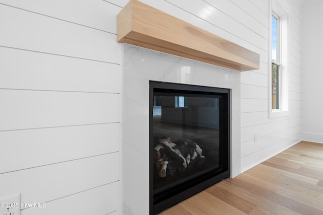 details with hardwood / wood-style flooring, a high end fireplace, and wood walls