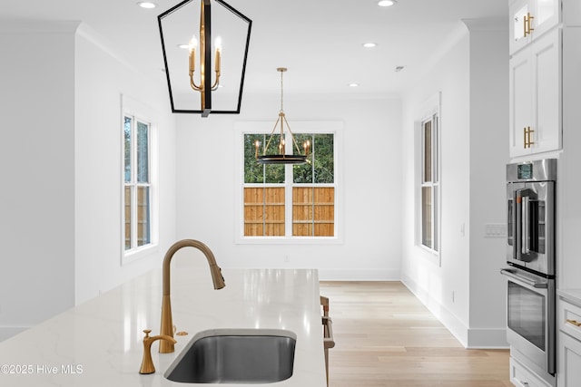 kitchen with white cabinetry, crown molding, pendant lighting, and double oven