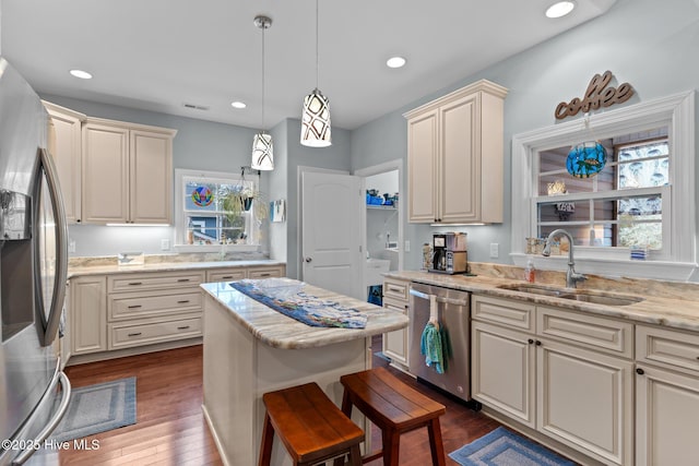 kitchen featuring sink, cream cabinets, hanging light fixtures, and appliances with stainless steel finishes