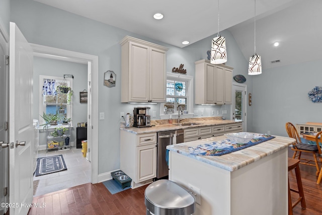 kitchen with a kitchen island, dark hardwood / wood-style floors, pendant lighting, sink, and stainless steel dishwasher