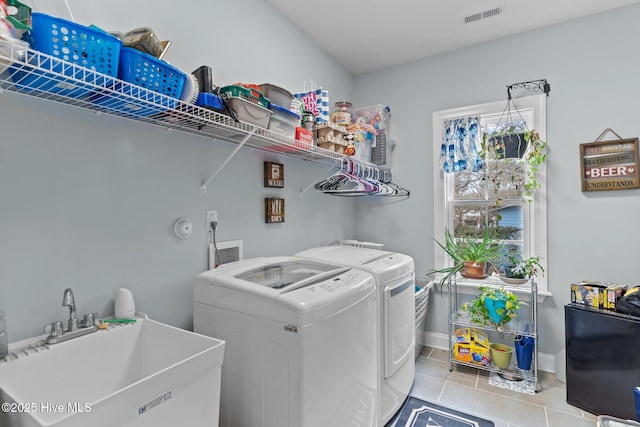 clothes washing area with separate washer and dryer, sink, and light tile patterned floors