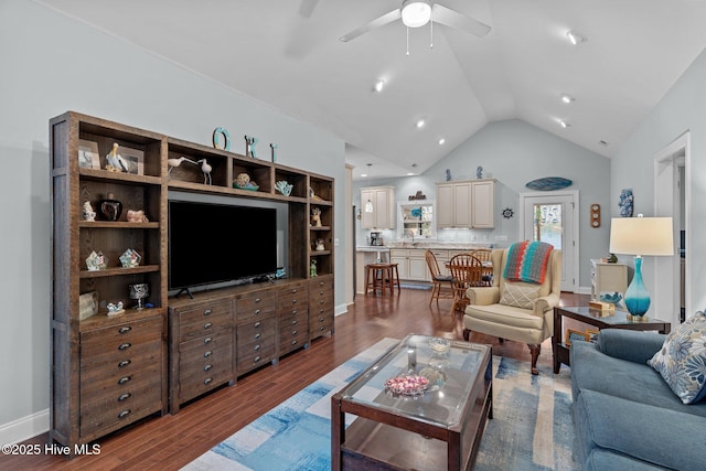 living room with hardwood / wood-style flooring, ceiling fan, and vaulted ceiling