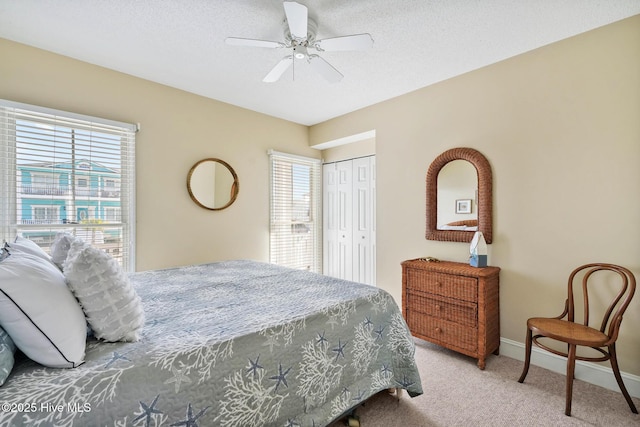 carpeted bedroom with ceiling fan, a closet, and a textured ceiling