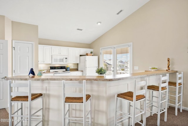 kitchen with white cabinetry, lofted ceiling, a kitchen bar, and white appliances