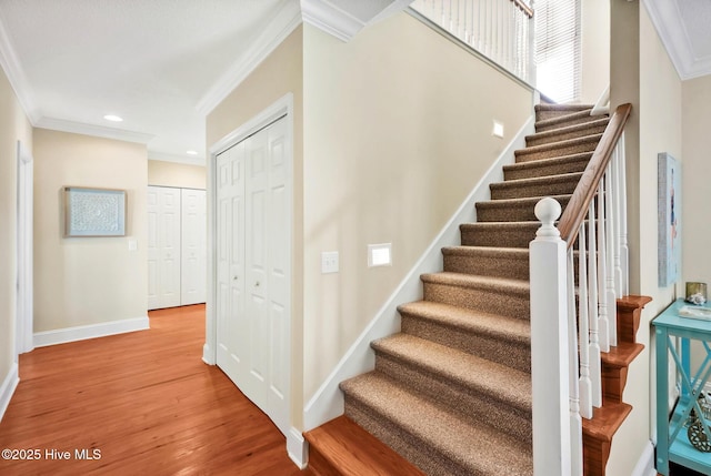 stairs with wood-type flooring and ornamental molding