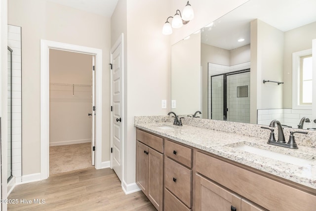 68 Tee Dr, Selma, NC 27576 - bathroom featuring a spacious closet, wood finished floors, a sink, and a stall shower