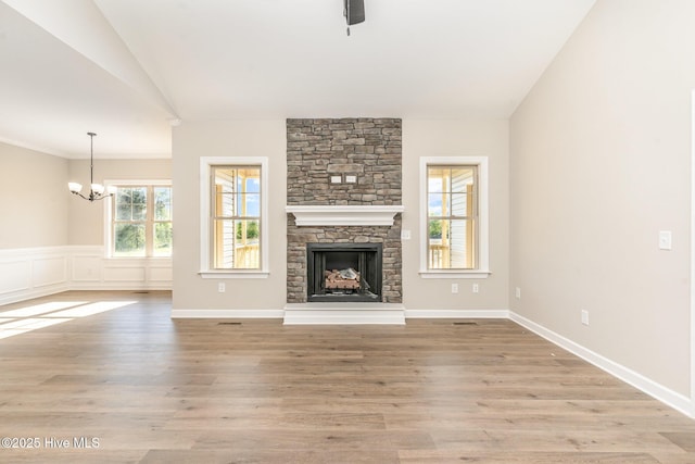 68 Tee Dr, Selma, NC 27576 - unfurnished living room featuring light wood-type flooring, vaulted ceiling, a fireplace, and a notable chandelier