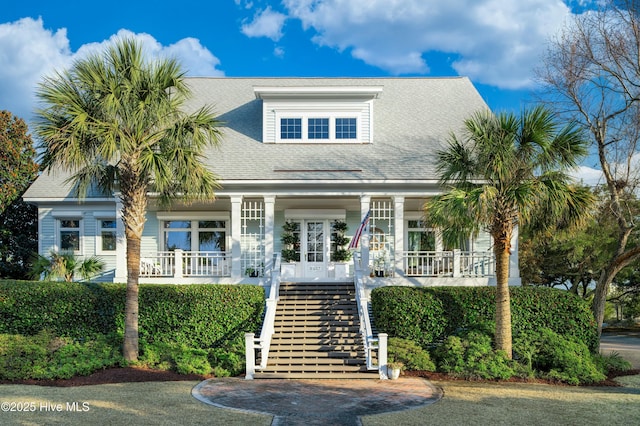 view of front of home with roof with shingles, stairway, and covered porch