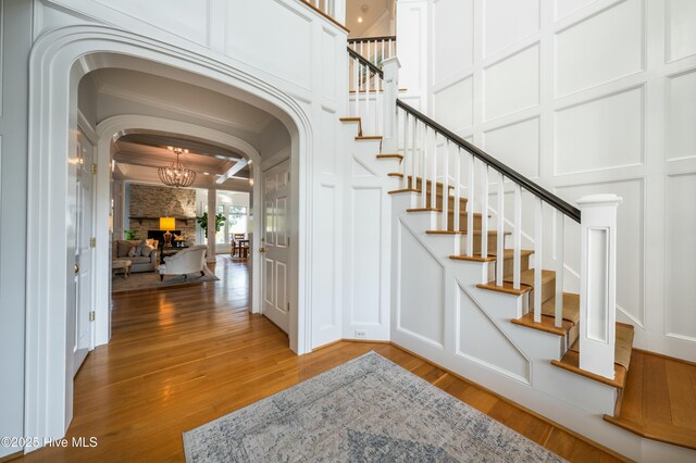 entryway featuring stairs, a high ceiling, a notable chandelier, and a decorative wall