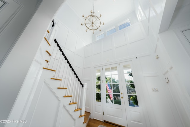 foyer entrance featuring a decorative wall, a notable chandelier, stairway, and a wealth of natural light