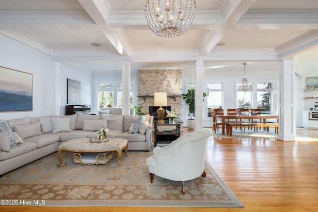 living room featuring an inviting chandelier, beamed ceiling, ornate columns, a large fireplace, and wood finished floors