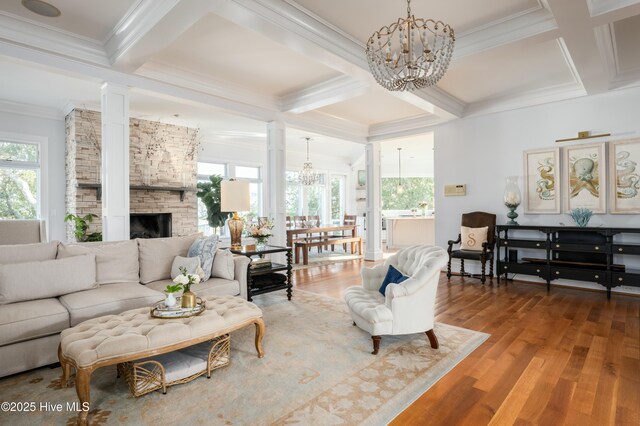 living area with a fireplace, wood finished floors, beam ceiling, and ornate columns