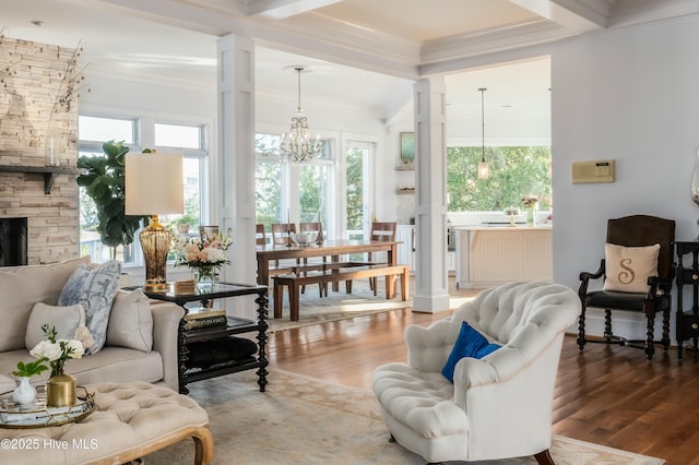 living room featuring beamed ceiling, an inviting chandelier, crown molding, and wood finished floors