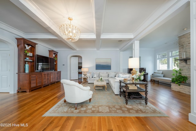 living area with arched walkways, wood finished floors, coffered ceiling, a notable chandelier, and beam ceiling