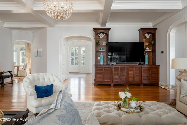 living room featuring coffered ceiling, arched walkways, wood finished floors, and an inviting chandelier