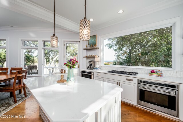 kitchen with white cabinets, decorative backsplash, appliances with stainless steel finishes, crown molding, and a sink