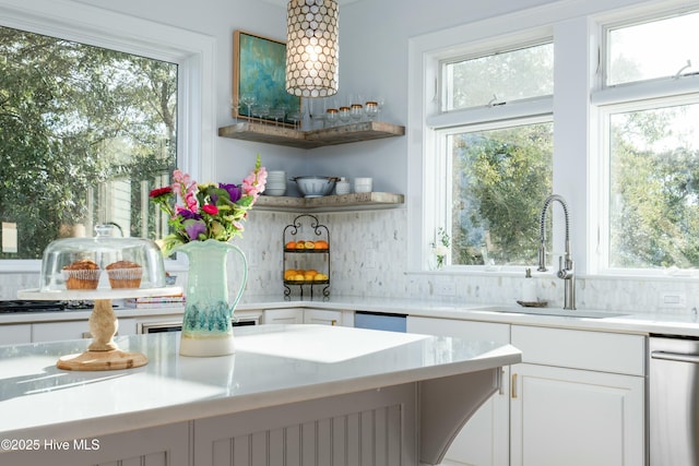 kitchen with light countertops, tasteful backsplash, plenty of natural light, and a sink