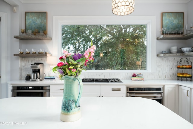 kitchen with open shelves, plenty of natural light, and stainless steel oven