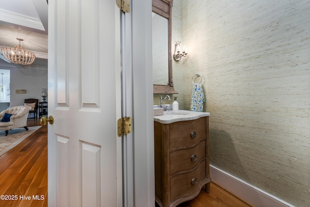 half bathroom with wood finished floors, vanity, and a notable chandelier