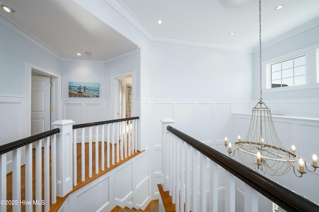 corridor with ornamental molding, an upstairs landing, a decorative wall, a notable chandelier, and recessed lighting