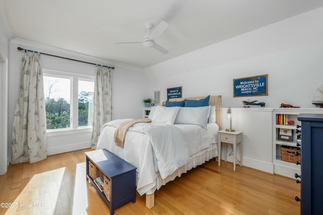 bedroom featuring ceiling fan, light wood finished floors, ornamental molding, and visible vents