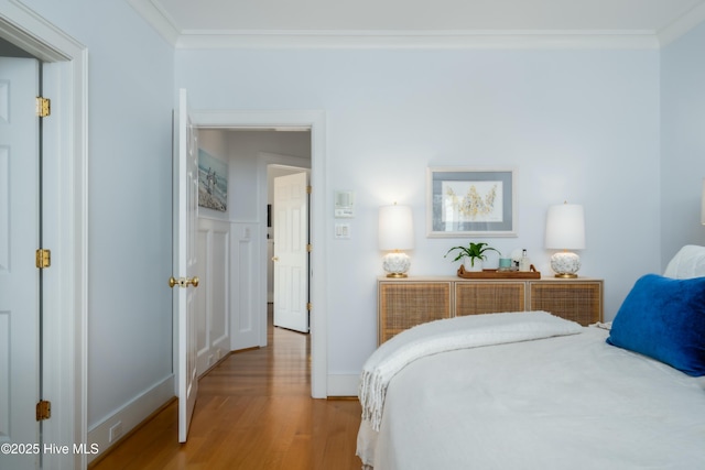 bedroom with baseboards, crown molding, and wood finished floors