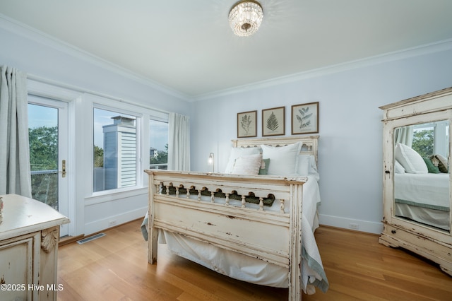 bedroom featuring ornamental molding, light wood-type flooring, visible vents, and baseboards