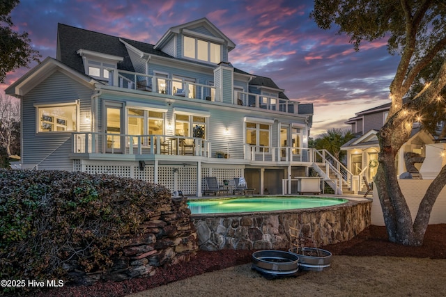 back of property at dusk with stairway and a balcony